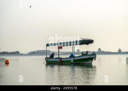 Barca locale parcheggiata in Sharjah Corniche con sfondo di enormi grattacieli Foto Stock