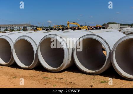 Grandi tubi in cemento per la costruzione di impianti di drenaggio per edifici industriali in cantiere. Foto Stock