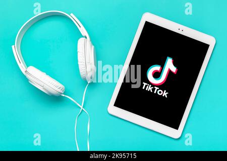 Bangkok, Thailandia. Ottobre 2022 Tablet Tik Tok applicazione icona, logo su schermo e cuffie wireless su sfondo colorato trendy social network concetto Flat Lay Top view. Foto Stock