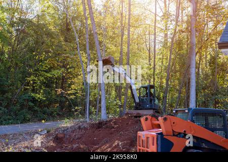 Utilizzando le minipale del trattore, gli alberi sono stati sradicati da un pezzo di terreno per fare il posto per lo sviluppo di alloggi su di esso Foto Stock