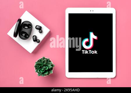 Bangkok, Thailandia. Ottobre 2022 Tablet Tik Tok applicazione icona, logo su schermo e cuffie wireless su sfondo colorato trendy social network concetto Flat Lay Top view. Foto Stock