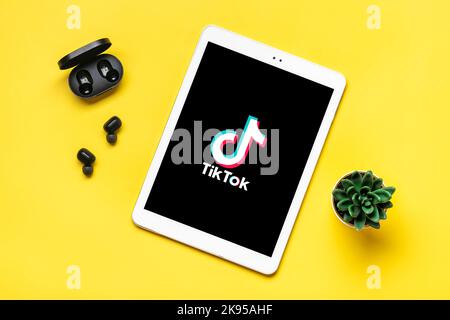 Bangkok, Thailandia. Ottobre 2022 Tablet Tik Tok applicazione icona, logo su schermo e cuffie wireless su sfondo colorato trendy social network concetto Flat Lay Top view. Foto Stock