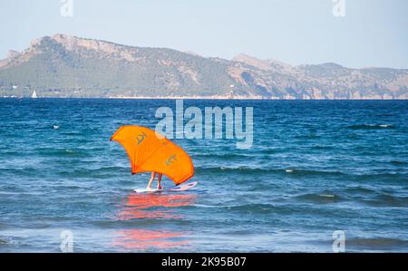 Surfista a bordo con aquilone arancione a Pollenca, Maiorca Foto Stock