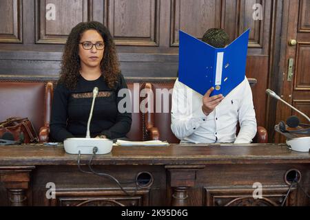 Amburgo, Germania. 26th Ott 2022. L'imputato (r) siede accanto a un interprete nella sala del tribunale prima dell'inizio del processo, tenendo una cartella blu davanti al suo volto. Il bambino di 27 anni è sottoposto a un processo per tentato massacro. Si dice che il convenuto abbia ferito fatalmente il suo partner con un coltello nell'ottobre 2021. Fuggì attraverso i tetti adiacenti e fu arrestato a Parigi il 11 novembre 2021, con un mandato d'arresto internazionale, e trasferito in Germania. Credit: Georg Wendt/dpa/Alamy Live News Foto Stock