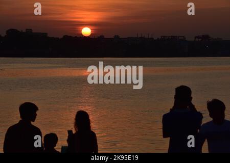 Kolkata, India. 25th Ott 2022. La gente osserva l'eclissi solare parziale durante il tramonto attraverso il fiume di Ganges o Hooghly sullo skyline di Kolkata il 25 ottobre 2022, in Kolkata, India. (Credit Image: © Biswarup Gangully/eyepix via ZUMA Press Wire) Foto Stock