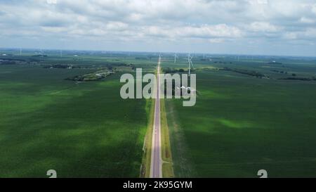 Un'immagine aerea del primo piano verde con turbine eoliche in una giornata nuvolosa Foto Stock
