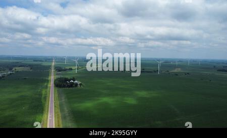 Un'immagine aerea del primo piano verde con turbine eoliche in una giornata nuvolosa Foto Stock