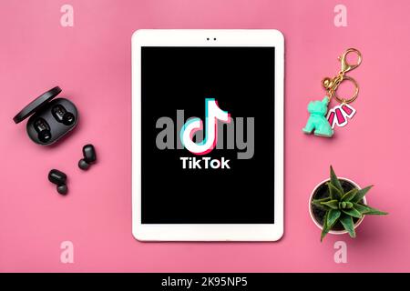 Bangkok, Thailandia. Ottobre 2022 Tablet Tik Tok applicazione icona, logo su schermo e cuffie wireless su sfondo colorato trendy social network concetto Flat Lay Top view. Foto Stock