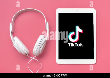 Bangkok, Thailandia. Ottobre 2022 Tablet Tik Tok applicazione icona, logo su schermo e cuffie wireless su sfondo colorato trendy social network concetto Flat Lay Top view. Foto Stock