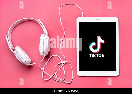 Bangkok, Thailandia. Ottobre 2022 Tablet Tik Tok applicazione icona, logo su schermo e cuffie wireless su sfondo colorato trendy social network concetto Flat Lay Top view. Foto Stock