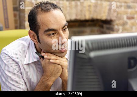 L'Agenzia dei media: Al monitor. Un lavoratore maturo dell'ufficio che si concentra candidamente sullo schermo del suo computer. Da una serie di immagini correlate. Foto Stock