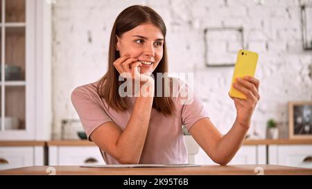 Una donna caucasica che ha una videochiamata da casa Foto Stock
