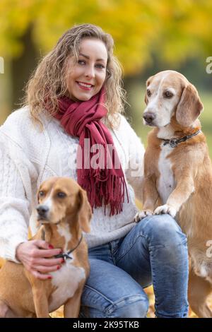 Ritratto di una giovane donna in un vestito autunnale con i suoi due animali domestici. Foto Stock