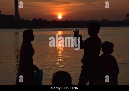 Kolkata, India. 25th Ott 2022. 25 ottobre 2022, Kolkata, India: La gente guarda l'eclissi solare parziale durante il tramonto attraverso il fiume Ganges o Hooghly sullo skyline di Kolkata il 25 ottobre 2022, a Kolkata, India. (Foto di Biswarup Gangully/Eyepix Group/Sipa USA). Credit: Sipa USA/Alamy Live News Foto Stock