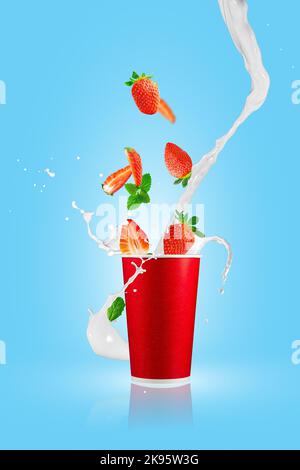 Fragole che cadono nella tazza da asporto di carta con schizzi di latte. Frullato di fragola. Foto Stock