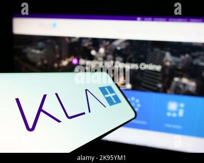 Cellulare con il logo della società americana di semiconduttori KLA Corporation sullo schermo di fronte al sito web aziendale. Messa a fuoco a sinistra del display del telefono. Foto Stock