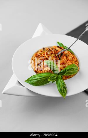 Spaghetti tonno pasta basilico piatto triangolare forma ardesia tavolo piuttosto appetitoso Foto Stock
