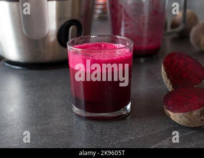 Succo di barbabietola appena spremuto in un bicchiere da bere sul tavolo da cucina Foto Stock