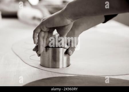 Donna che lavora all'interno di una fabbrica di pasta o di un ristorante e che stampa ravioli freschi, culurgiones, agnolotti. Pasta fresca fatta in casa Foto Stock