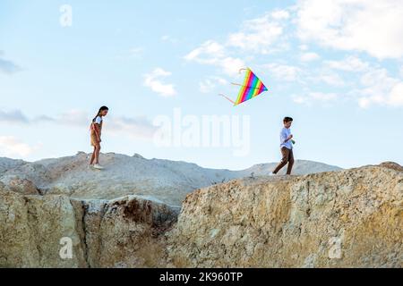 Gli adolescenti corrono attraverso le montagne con il concetto di vacanza estiva di volo del aquilone. Foto Stock