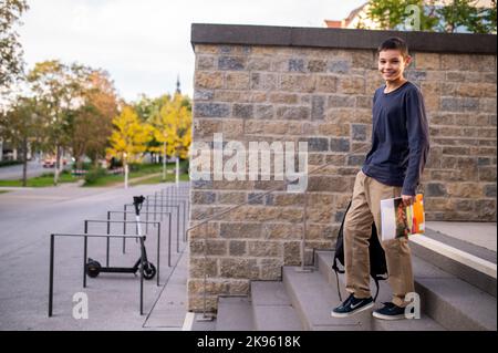 Ragazzo giovane sorridente che cammina giù per i gradini Foto Stock