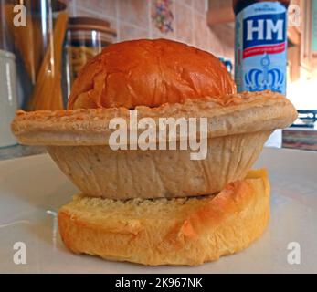 Wigan Lancashire Pie Burger, una bistecca o una torta di carne su un muffin fondo forno, con bottiglia di salsa HP Foto Stock