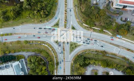 Incroci stradali, città moderna. Vista dall'alto al trafficato incrocio stradale in Malesia. Auto e camion colorati che guidano dritto in entrambe le direzioni Foto Stock