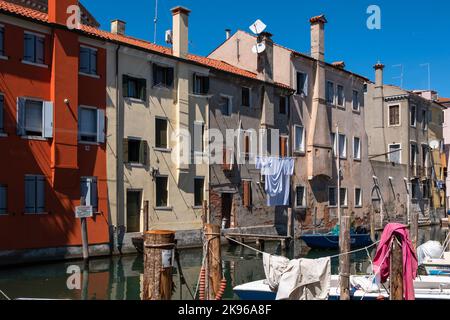 Vista sul canale principale di Chioggia, conosciuta come la piccola Venezia, con barche ormeggiate lungo le banchine fiancheggiate da edifici di architettura tradizionale italiana. Chioggia, città della laguna veneta che ospita molti turisti in visita a Venezia, non è stata inclusa nel perimetro comunale veneziano. I turisti che vi soggiornano dovranno pagare la tassa ogni volta che visitano Venezia dal 16 gennaio 2023. Foto Stock