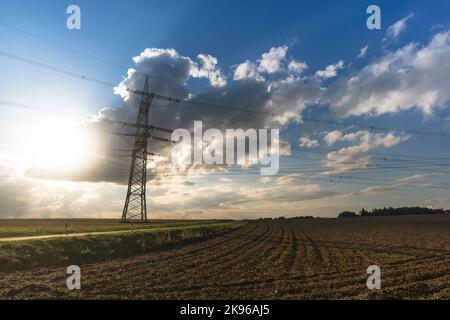 Pilone elettrico per la trasmissione e il trasferimento di corrente di alta tensione attraverso paesaggi naturali di fronte a un cielo nuvoloso Foto Stock