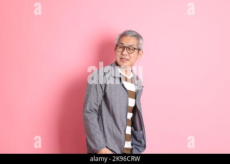 Il 40s adulto asiatico uomo stnading su sfondo rosa con abiti casual. Foto Stock