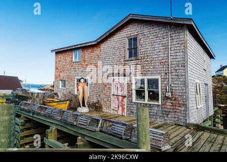 Immagine panoramica della comunità di Peggys Cove che si trova intorno a St Margarets Bay, Nuova Scozia, con cieli azzurri e riflessi chiari nelle acque della baia Foto Stock