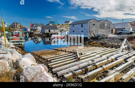 Immagine panoramica della comunità di Peggys Cove che si trova intorno a St Margarets Bay, Nuova Scozia, con cieli azzurri e riflessi chiari nelle acque della baia Foto Stock