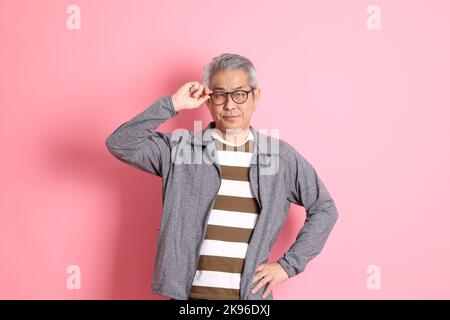 Il 40s adulto asiatico uomo stnading su sfondo rosa con abiti casual. Foto Stock