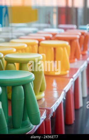 Una verticale di una fila di sgabelli colorati impilati uno sopra l'altro. Foto Stock