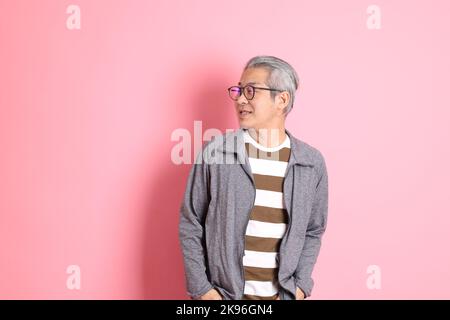 Il 40s adulto asiatico uomo stnading su sfondo rosa con abiti casual. Foto Stock