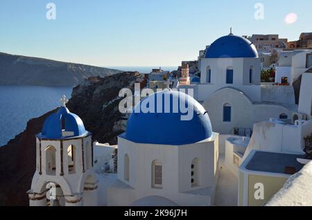 Le chiese a cupola blu sulla scogliera di Oia con il mare Egeo e la Caldera sullo sfondo a Santorini. Foto Stock