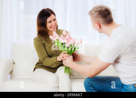 Gli uomini salutano la moglie con bouquet floreale Foto Stock