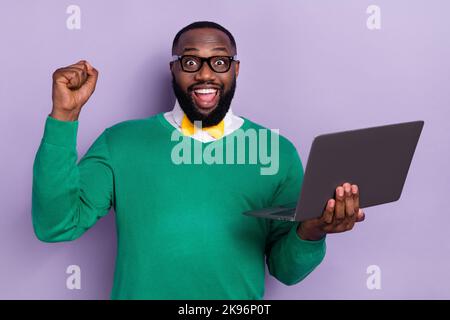 Foto di gioiosa ridere freelancer sollevare pugni in vittoria firmato contratto di successo isolato su sfondo di colore viola Foto Stock