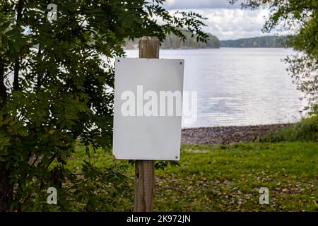 Cartello bianco vuoto accanto ad una spiaggia in autunno Foto Stock