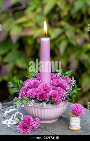 composizione floreale con fiori di crisantemo rosa e candela Foto Stock