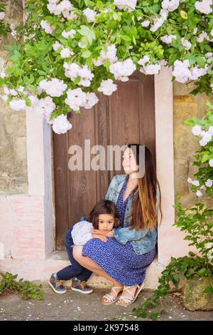 Donna e bel bambino seduto vicino alla porta antica Foto Stock