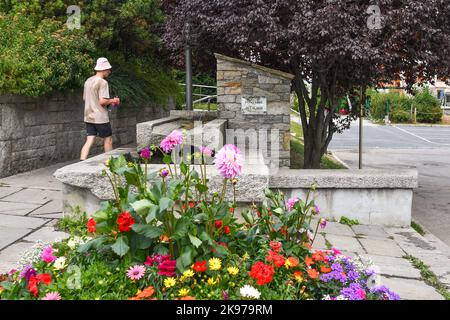 Un escursionista si rifornisce di acqua dolce alla fontana dedicata al gemellaggio tra le città di Chamonix e Cilaos, Chamonix, Francia Foto Stock