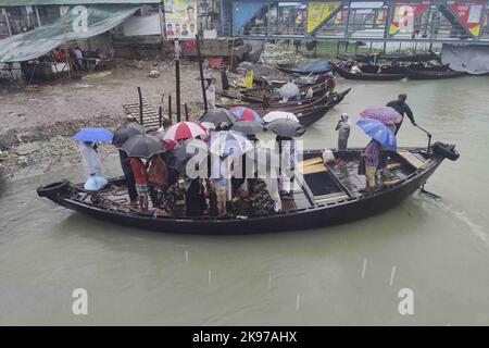 Dhaka, Bangladesh. 24th Ott 2022. I passeggeri del Bangladesh attraversano il fiume Buriganga mentre detengono ombrelli durante una forte pioggia e condizioni difficili causate dal ciclone Sitrang a Dhaka, Bangladesh, 24 ottobre 2022. Secondo la Bangladesh Inland Water Transport Authority (BIWTA) e il Dipartimento di Meteorologia del Bangladesh, il trasporto di acque interne è stato sospeso in quanto il ciclone Sitrang si avvicina dovrebbe attraversare la parte sud-sud-ovest del distretto di Barishal e Chattogram entro il 25 ottobre. Il Bangladesh Met Office ha avvertito che la tempesta ciclonica potrebbe intensificarsi ulteriormente e trasformarsi in un grave ciclone Foto Stock