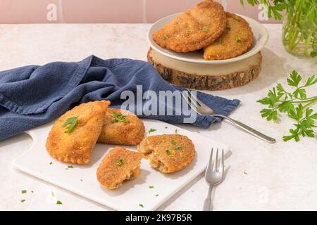 Polpettine di carne e foglie di prezzemolo su piatti di ceramica bianca in una cucina da banco. Foto Stock