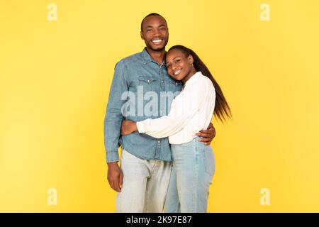 Felice coppia afro-americana che abbraccia posa su sfondo giallo Foto Stock