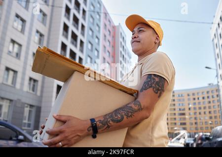 Vista laterale ritratto della scatola di contenimento dell'operatrice di consegna femminile in città Foto Stock