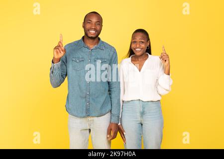 Sposi afro-americani felici che puntano le dita su sopra lo sfondo giallo Foto Stock