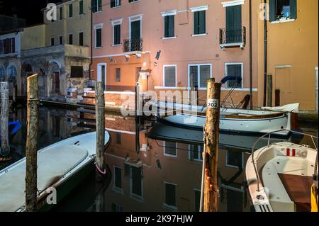 Chioggia, Italia. 20th ago, 2022. Vista generale dei canali di Chioogia (soprannominata "piccola Venezia") con le barche e gli edifici riflessi nell'acqua sotto la luce artificiale al crepuscolo. Chioggia, città della laguna veneta che ospita molti turisti in visita a Venezia, non è stata inclusa nel perimetro comunale veneziano. I turisti che vi soggiornano dovranno pagare la tassa ogni volta che visitano Venezia dal 16 gennaio 2023. (Foto di Laurent Coust/SOPA Images/Sipa USA) Credit: Sipa USA/Alamy Live News Foto Stock