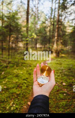 Mano con bussola in terreno forestale. Concetto di viaggio POV Foto Stock