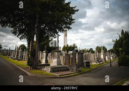 La Torre rotonda e le lapidi nel cimitero di Glasnevin, Dublino, Irlanda. Foto Stock